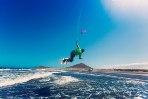 Un deportista realiza una acrobacia de kite surf en la playa de El Médano